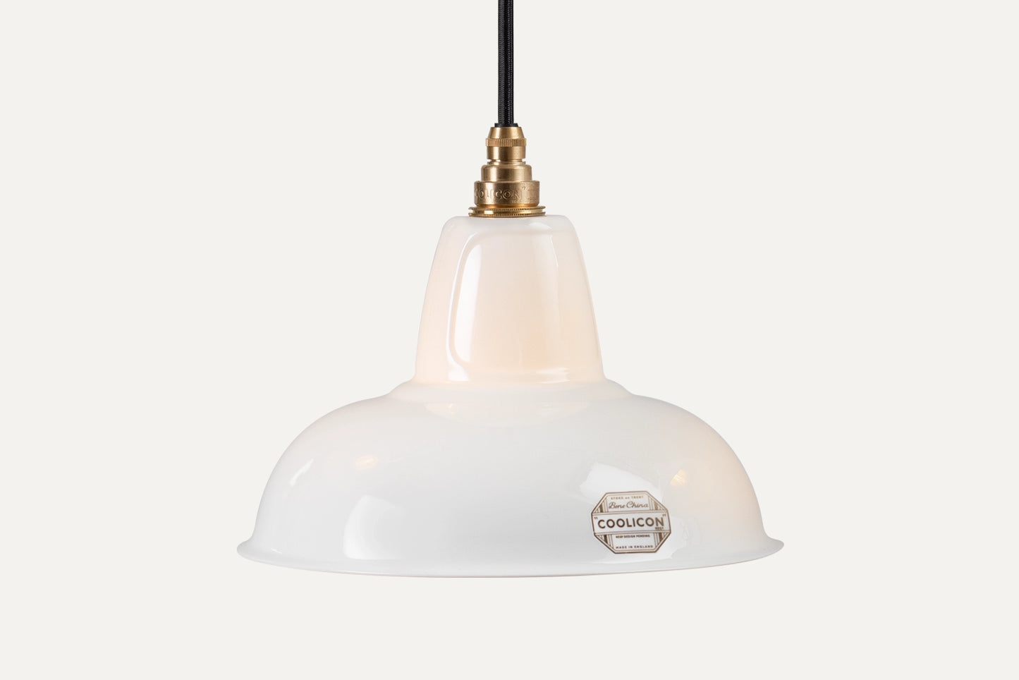 A Fine Bone China Silhouette Coolicon shade with a Signature Brass pendant set hangs over a light grey background